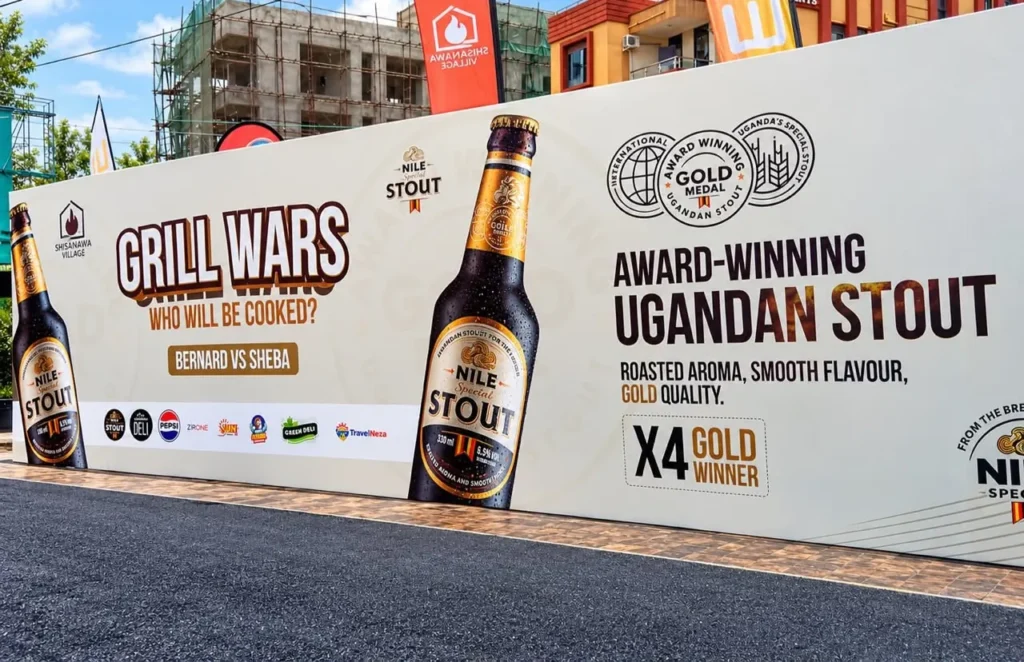 Printed event hoarding along a street with a sponsor strip